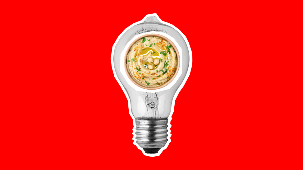 A bowl of hummus inside a light bulb on a red background. 