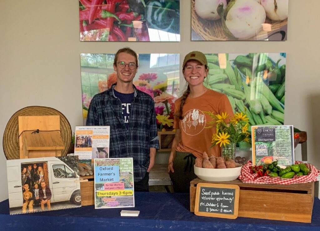 Students stand behind a display table with information about the school's farm.