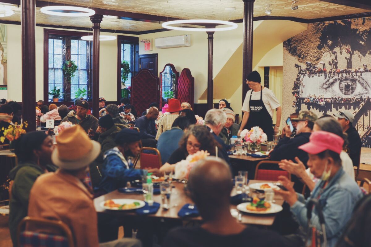A group of people gather in a large dining room to share a meal together.